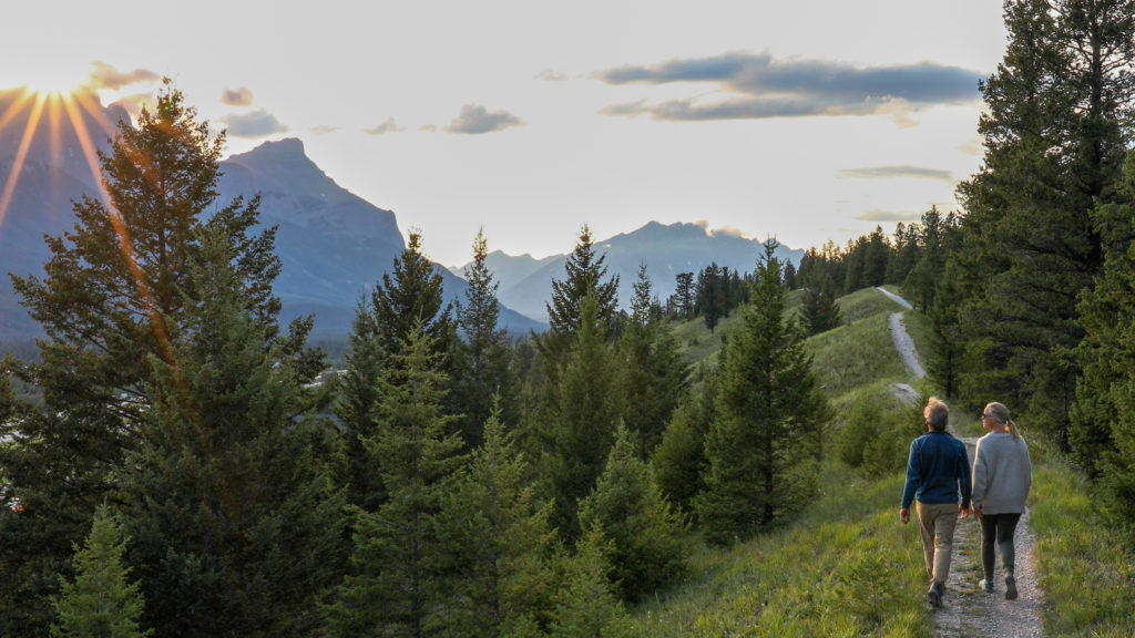 Older couple walk down trail at sunrise